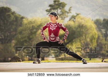Stock Photo - Caucasian runner stretching in park. Fotosearch