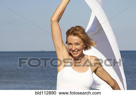 Stock Image - Caucasian woman playing with scarf on beach. Fotosearch