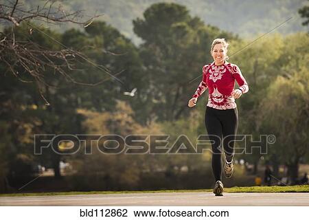 Stock Image - Caucasian woman running in park. Fotosearch