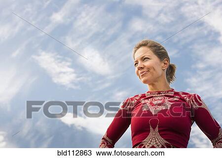 Stock Image - Caucasian woman standing under blue sky. Fotosearch