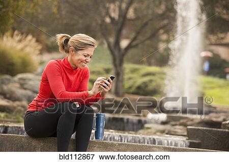 Caucasian woman using cell phone in park View Large Photo Image Stock Photo - Caucasian woman using cell phone in park. Fotosearch