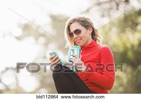 Picture - Caucasian woman using cell phone outdoors. Fotosearch
