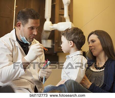 Dentist and nurse examining boy's teeth in office View Large Photo Image Stock Image - Dentist and nurse examining boy's teeth in office. Fotosearch