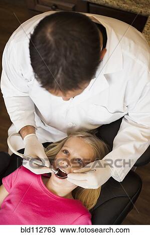 Dentist examining girl's teeth in office View Large Photo Image Stock Image - Dentist examining girl's teeth in office. Fotosearch