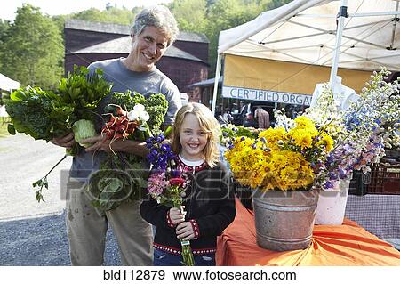 Stock Photo - Father and daughter buying flowers at farmers market. Fotosearch
