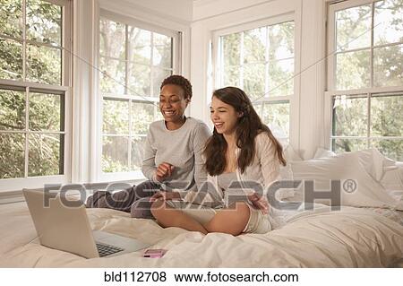 Stock Photo - Friends using laptop in bed together. Fotosearch