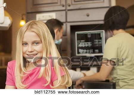 Stock Photography - Girl with braces smiling in dentist's office. Fotosearch