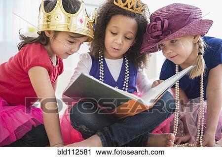 Stock Image - Girls reading book together. Fotosearch