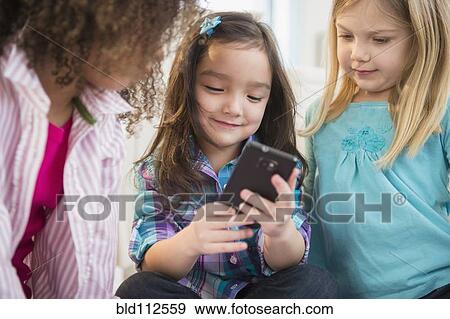 Stock Photo - Girls using cell phone together. Fotosearch