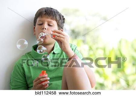 Stock Photo - Hispanic boy blowing bubbles indoors. Fotosearch