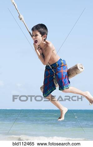 Stock Photography - Hispanic boy playing on swing outdoors. Fotosearch
