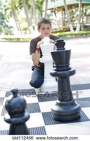 Stock Photograph - Hispanic boy playing with oversized chess set. Fotosearch
