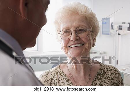 Stock Photo - Hispanic doctor talking with older patient. Fotosearch