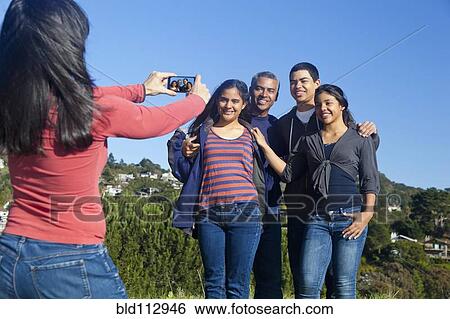 Stock Photograph - Hispanic family taking picture in park. Fotosearch