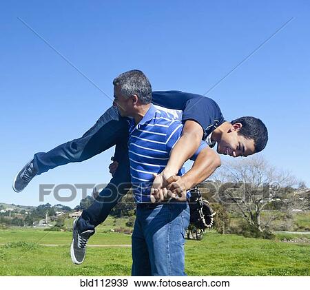 Stock Photo - Hispanic father and son playing in park. Fotosearch