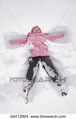 Picture - Hispanic girl making snow angel. Fotosearch