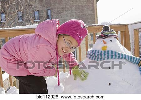 Stock Photograph - Hispanic girl making snowman. Fotosearch
