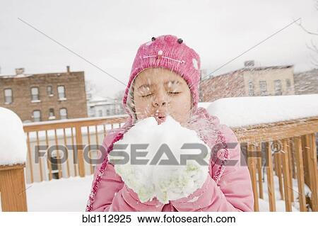 Stock Photography - Hispanic girl playing with snowball. Fotosearch