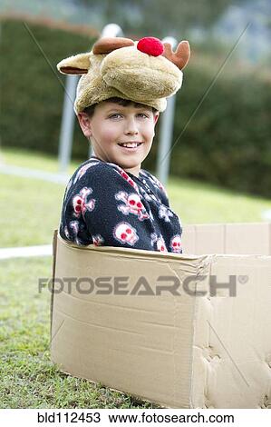 Stock Image - Hispanic girl sitting in cardboard box. Fotosearch