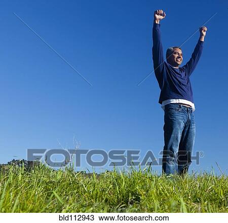 Stock Image - Hispanic man cheering outdoors. Fotosearch