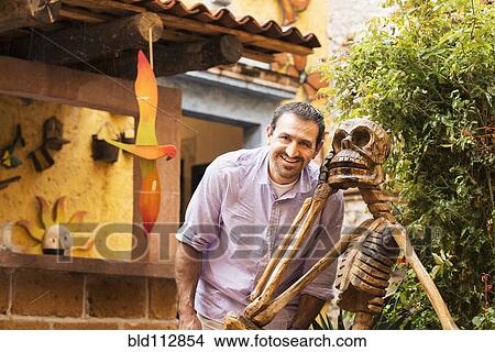 Hispanic man smiling by skeleton statue View Large Photo Image Picture - Hispanic man smiling by skeleton statue. Fotosearch