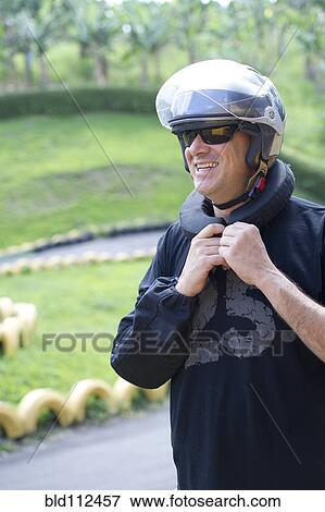 Stock Photo - Hispanic man tying on helmet. Fotosearch