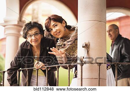 Stock Photo - Hispanic mother and daughter standing on porch. Fotosearch