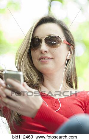 Stock Photo - Hispanic woman listening to mp3 player outdoors. Fotosearch
