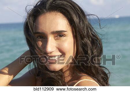 Stock Photo - Hispanic woman smiling on beach. Fotosearch
