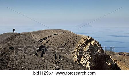 Stock Photo - Man walking on rock formations, Vulcano Isle, Sicily, Italy. Fotosearch