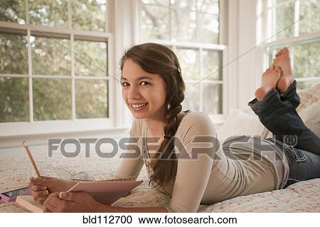 Mixed race girl laying in bed writing in journal View Large Photo Image Stock Image - Mixed race girl laying in bed writing in journal. Fotosearch
