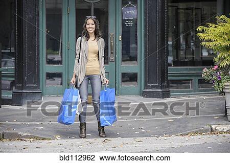 Mixed race woman carrying shopping bags View Large Photo Image Stock Image - Mixed race woman carrying shopping bags. Fotosearch