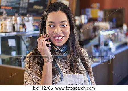 Stock Photography - Mixed race woman on telephone in coffee shop. Fotosearch