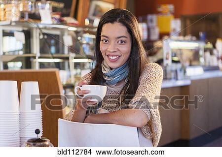 Mixed race woman sitting in coffee shop View Large Photo Image Picture - Mixed race woman sitting in coffee shop. Fotosearch
