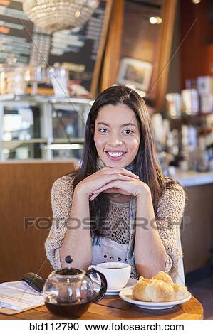 Mixed race woman sitting in coffee shop View Large Photo Image Stock Image - Mixed race woman sitting in coffee shop. Fotosearch