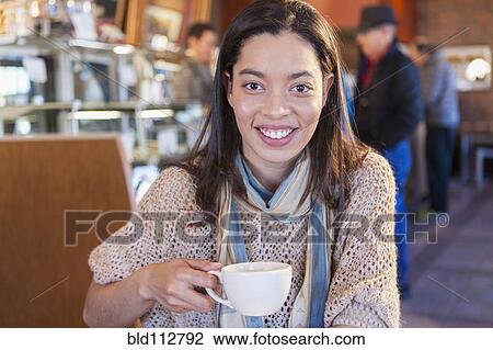 Stock Image - Mixed race woman sitting in coffee shop. Fotosearch