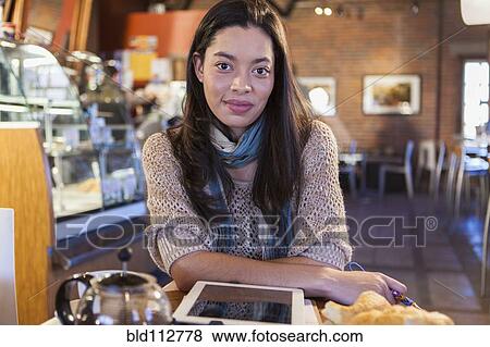 Stock Photo - Mixed race woman using tablet computer in coffee shop. Fotosearch