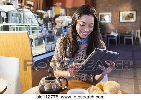 Mixed race woman using tablet computer in coffee shop View Large Photo Image Stock Photograph - Mixed race woman using tablet computer in coffee shop. Fotosearch