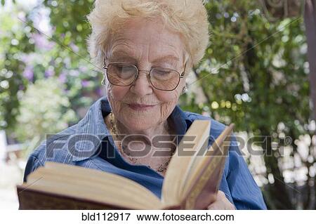 Stock Photo - Older Hispanic woman reading outdoors. Fotosearch