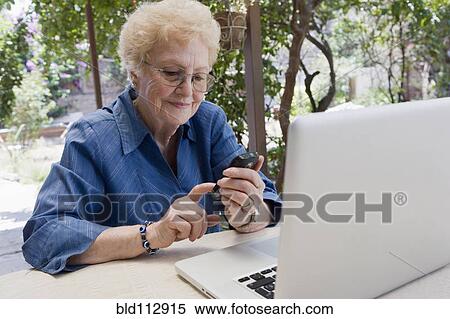 Stock Photography - Older Hispanic woman using cell phone outdoors. Fotosearch