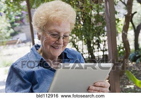 Older Hispanic woman using tablet computer outdoors View Large Photo Image Stock Photograph - Older Hispanic woman using tablet computer outdoors. Fotosearch