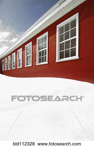 Stock Photo - Snow piled up outside red building. Fotosearch