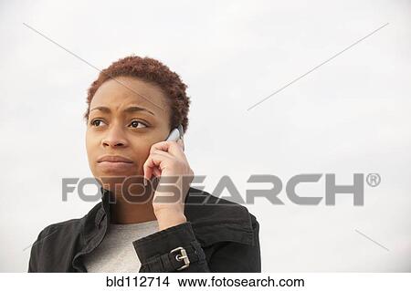 Picture - Uncertain African American woman talking on cell phone. Fotosearch