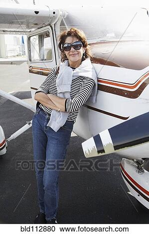 Stock Image - Woman leaning on airplane in runway. Fotosearch