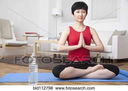 Woman meditating in living room View Large Photo Image Stock Photo - Woman meditating in living room. Fotosearch