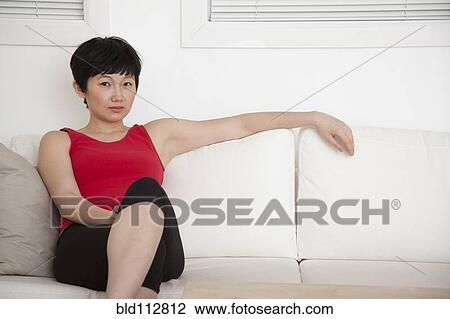 Woman relaxing on sofa in living room View Large Photo Image Stock Image - Woman relaxing on sofa in living room. Fotosearch