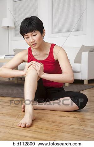 Stock Image - Woman stretching in living room. Fotosearch