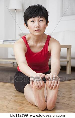 Stock Photo - Woman stretching in living room. Fotosearch