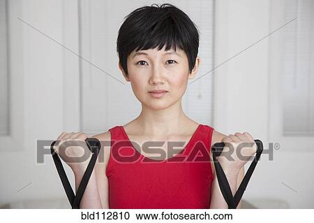 Woman using stretcher weights in living room View Large Photo Image Stock Image - Woman using stretcher weights in living room. Fotosearch