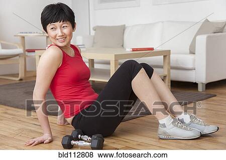 Woman with dumbbells sitting on living room floor View Large Photo Image Stock Photo - Woman with dumbbells sitting on living room floor. Fotosearch